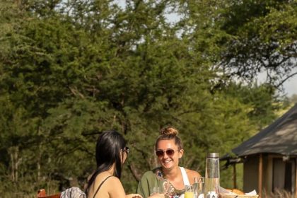 Guest on a Serengeti wellness safari mental reset departure sitting quietly at a Tanzania bush camp at dawn