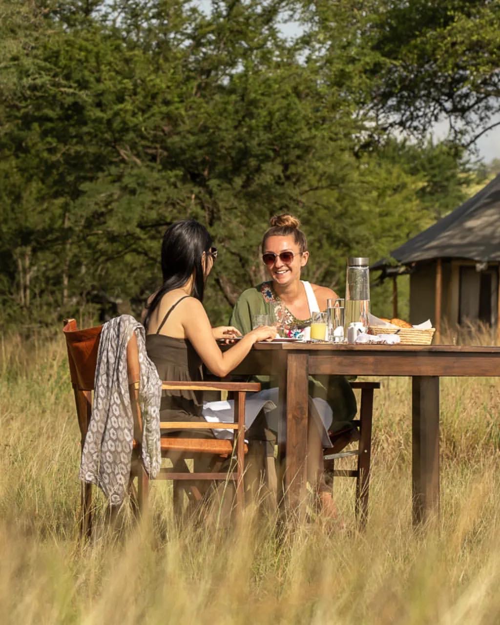 Guest on a Serengeti wellness safari mental reset departure sitting quietly at a Tanzania bush camp at dawn