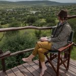 Solo Female traveller on a luxury safari in Tanzania watching wildlife from a private deck.