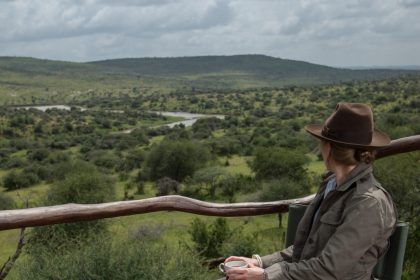 Solo Female traveller on a luxury safari in Tanzania watching wildlife from a private deck.