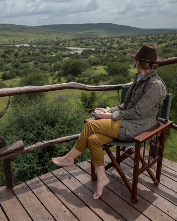 Solo Female traveller on a luxury safari in Tanzania watching wildlife from a private deck.